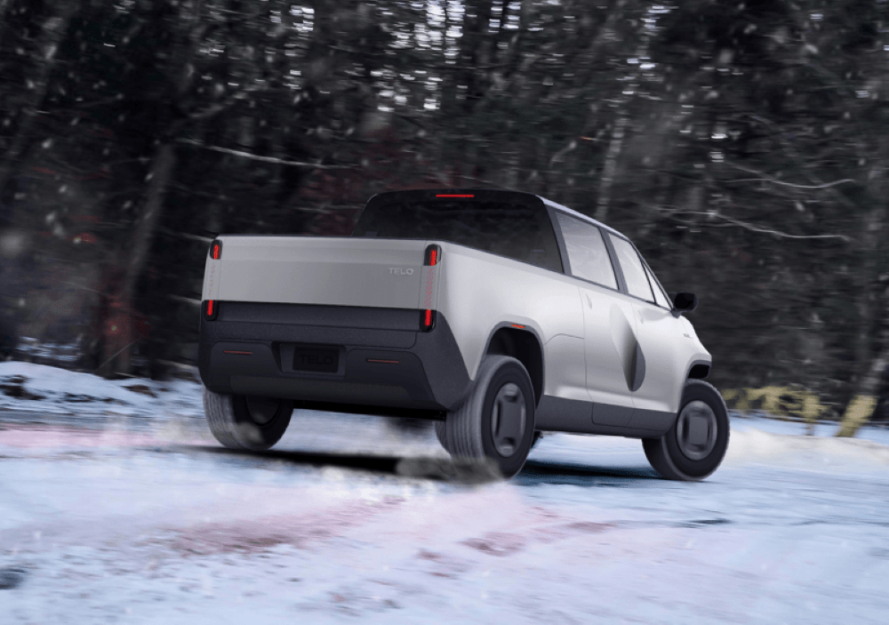 TELO Truck drifting through the snow with pine trees in the background.