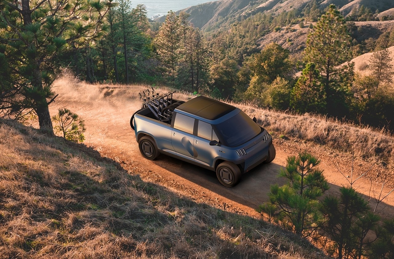 TELO Truck driving along a dirt alpine road with four mountain bikes in the bed.