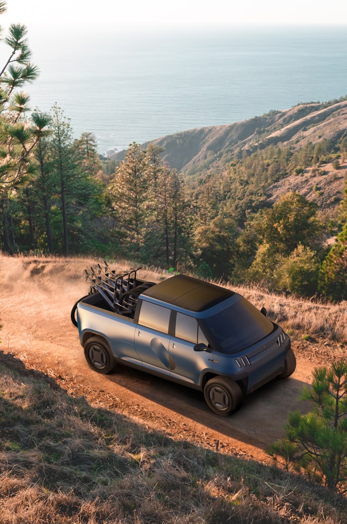 TELO Truck driving along a dirt alpine road with four mountain bikes in the bed.